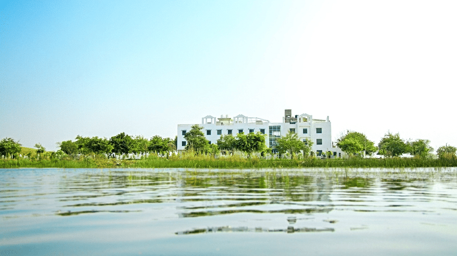 Grassfield Riviera Resort seen across the lake amid greenery, a lakeside wedding resort near Jaipur.