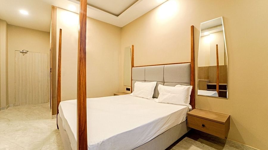 A bedroom at Grassfield Riveria Resort, Jaipur, with a four-poster bed, minimalist decor, and a private bathroom.