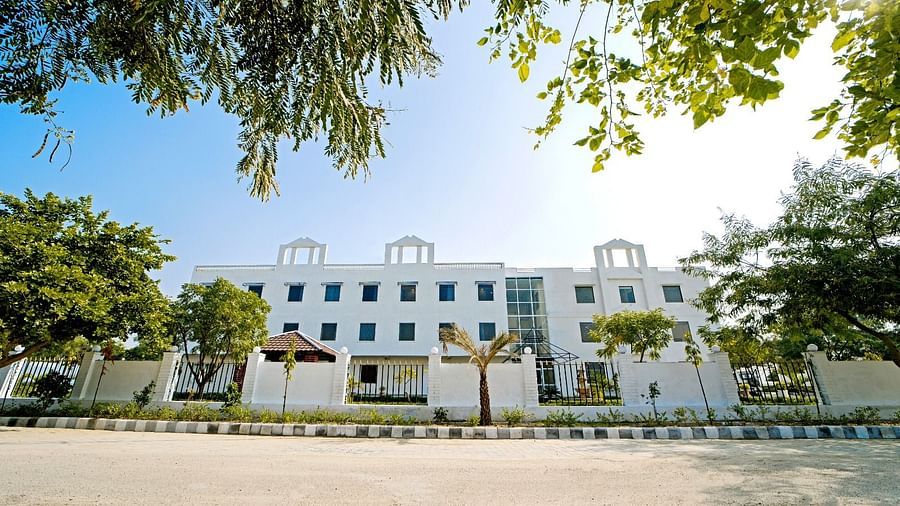 Front view of Grassfield Riveria Resort, Jaipur, surrounded by trees and clear skies, showcasing the modern building facade.