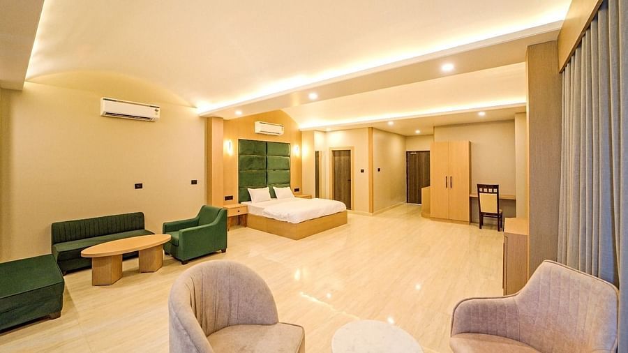 Spacious, well-lit room at Grassfield Riveria Resort, Jaipur, featuring comfortable seating, large bed, and modern amenities.