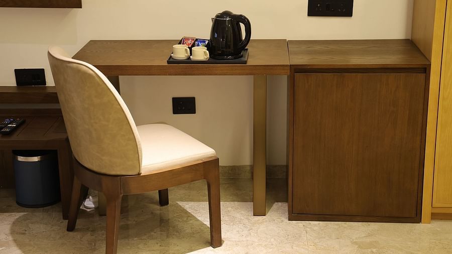 A well appointed writing desk area at Lords Eco inn Jamnagar Maheshwari Nagar with a chair and tea coffee making facilities.