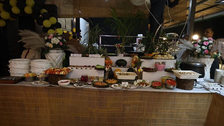 A lavish buffet spread is presented on a long table with various dishes and decorative elements - Lords Inn Vadodara
