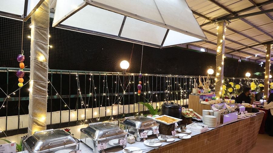 An outdoor dining area at night features buffet stations under illuminated canopies - Lords Inn Vadodara