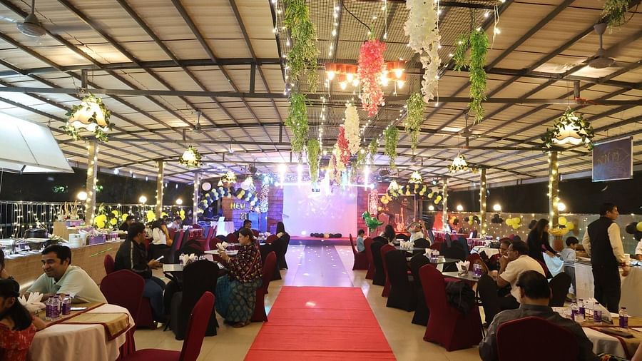 An outdoor event space is decorated with lights and a red carpet leading through seated guests - Lords Inn Vadodara