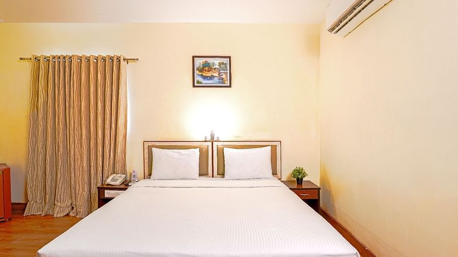 Hotel room with a double bed, minimalist decor, and air conditioning in Hyderabad near Ramoji Film City.