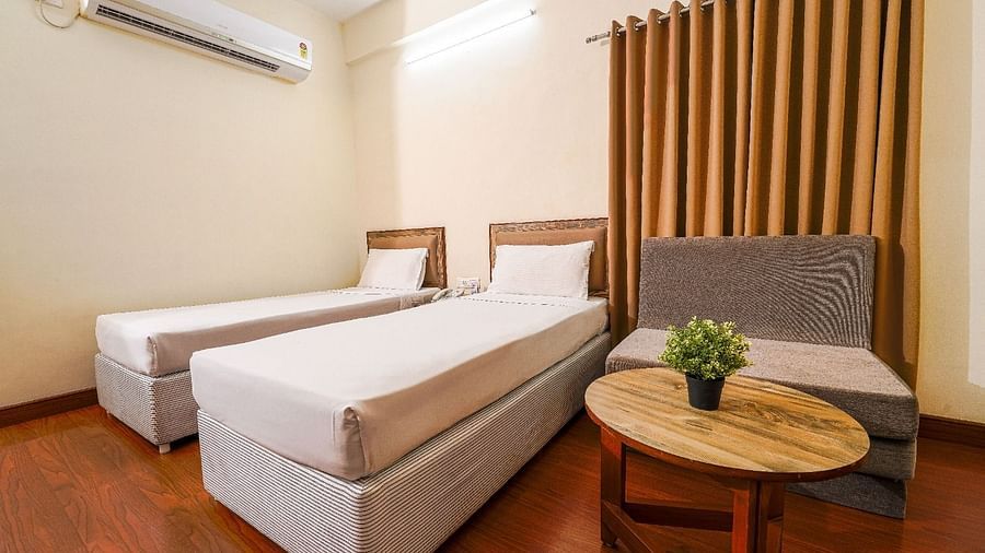 Hotel room with two single beds, a comfortable couch, and a coffee table in Hyderabad near Ramoji Film City.