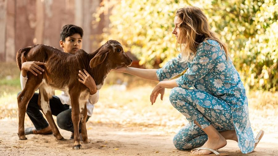 A woman petting goat as a boy holds it.