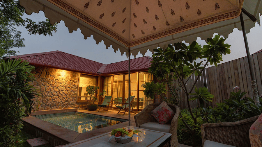 An outdoor seating area with a swimming pool in the corner at Surpura Bagh.
