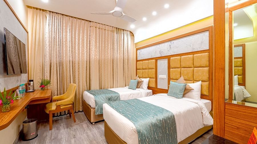 omfortable twin beds in a stylish hotel room, featuring soft lighting, a workspace, and large windows at Tara, Comfort Hotel in Hyderabad - Ramoji Film City.
