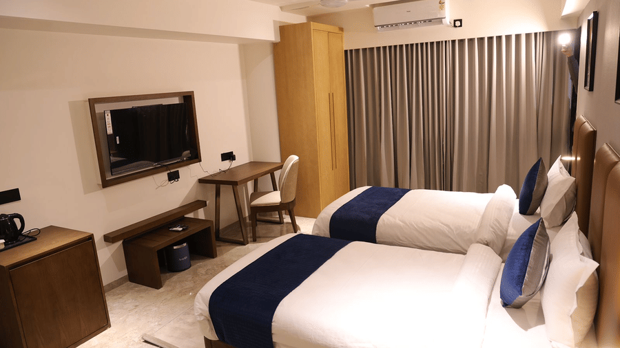 A spacious hotel room at Lords Studio Inn, Jamnagar with a large bed television and seating area.