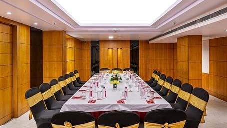 a boardroom meeting arrangement at a Banquet hall in Libra Lords Inn Jaipur with wood-panelled walls and ceiling lights