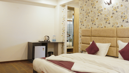 Bedroom of Lime Tree Hotels & Service Apartment Private Limited featuring a padded headboard, a mirrored wardrobe, and maroon bedding.