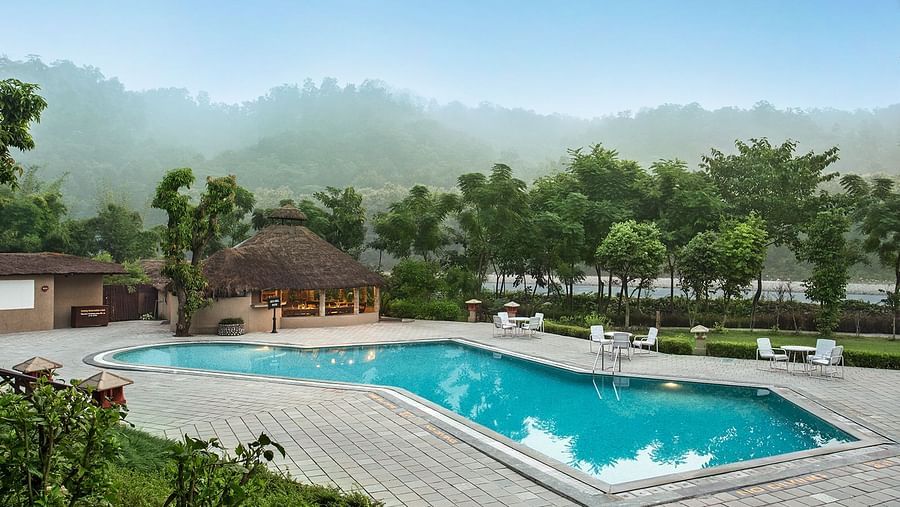 An image of swimming pool surrounded by huts and palm trees
