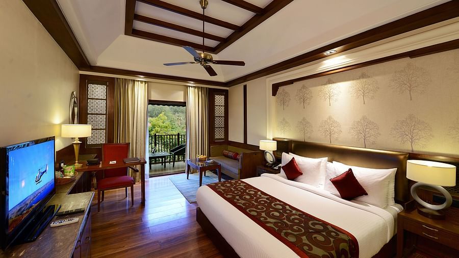 The interiors of our luxury cottages in Pushkar featuring a balcony, a comfortable bed, a desk and a television 