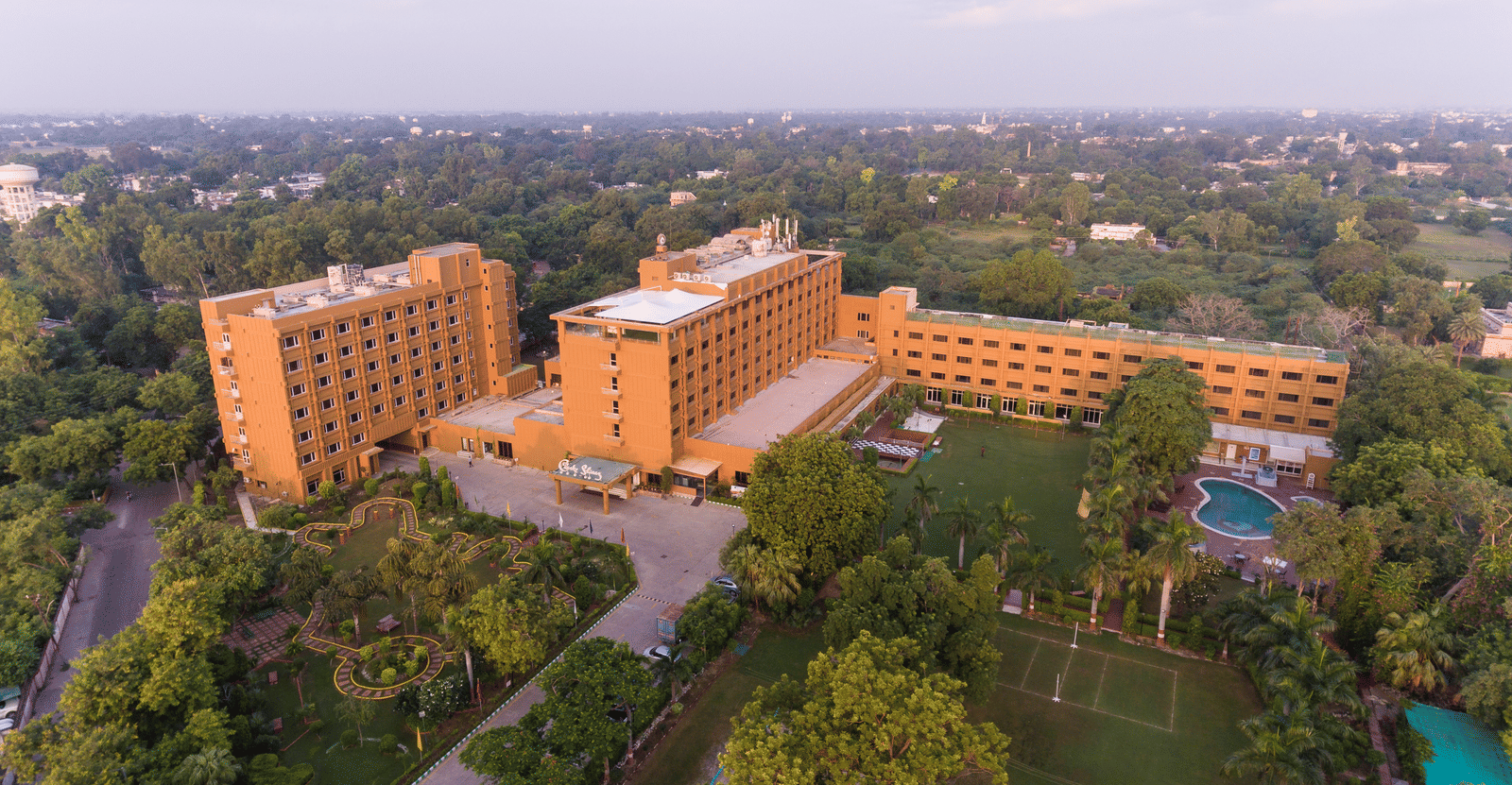 Agra Hotel Images of Hotel Clarks Shiraz, Agra, covered by trees as seen from above.