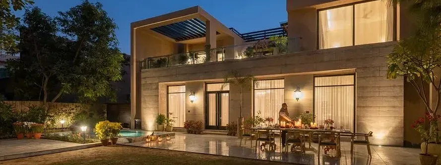 Exterior view of a lit-up building at night with outdoor seating at Karma Chalets.