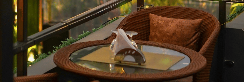 Two chairs facing each other on a terrace with warm lights besides it on a late evening.