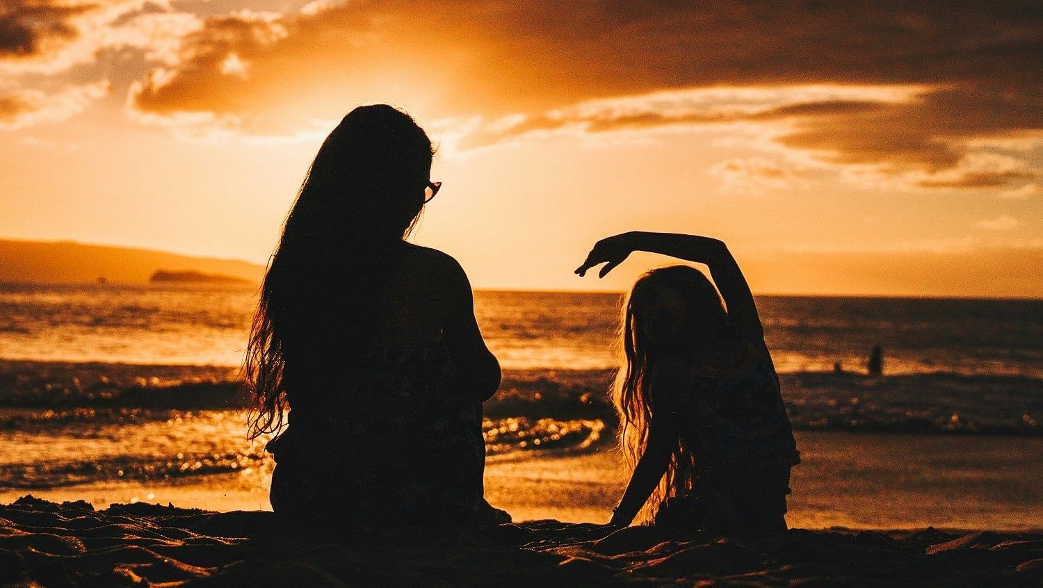 Two people sitting and chatting with a dramatic sunset behind them