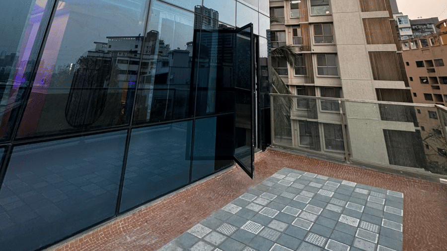 Upward angle of the blue-tinted glass exterior and outdoor terrace area.
