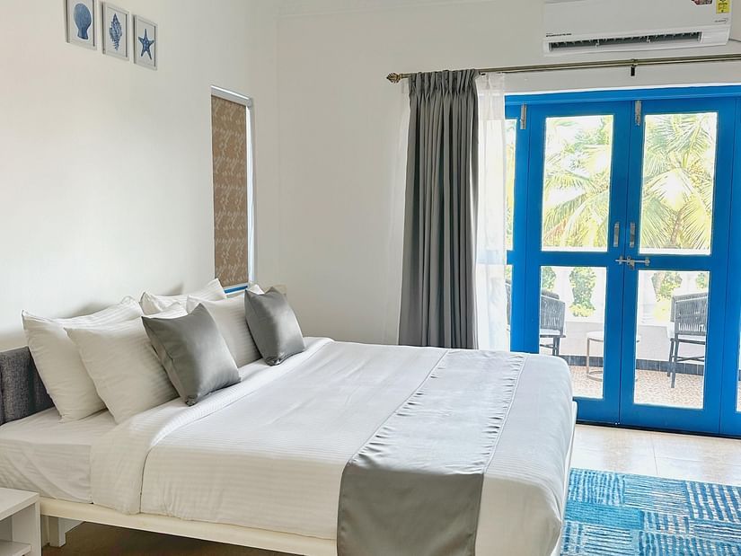 A king bed with blue door to the balcony inside one of the rooms at Azalea By Stone Wood Premier, Orlim