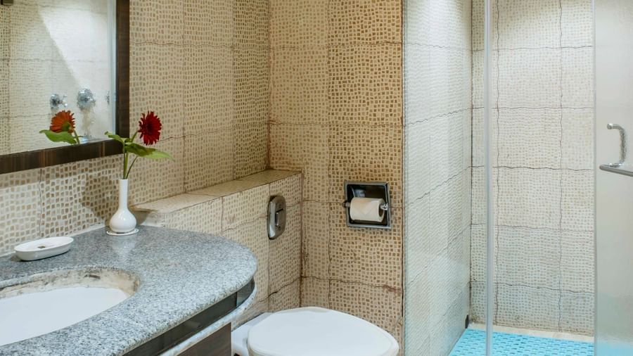 Clean and modern hotel bathroom with a sink, toilet, and glass-enclosed shower | The Citi Residenci Hotel Durgapur