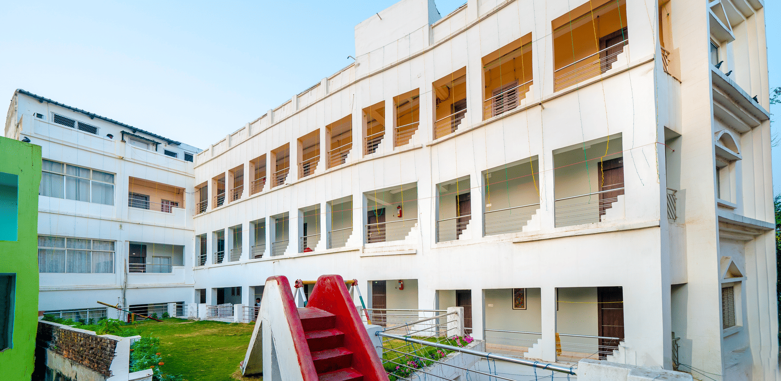 A wide exterior view of the multi-storey, white hotel building with rows of windows and balconies under a clear blue sky - Hotel Dolphin Puri