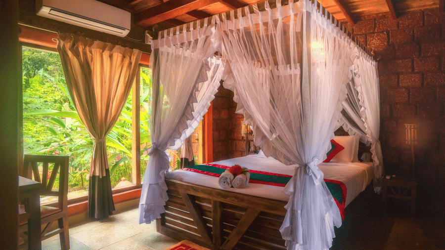 Pepper Pool Villa at Copper Edge, the best resort in Coorg, featuring a bed next to a seating area with the view of greenery outside