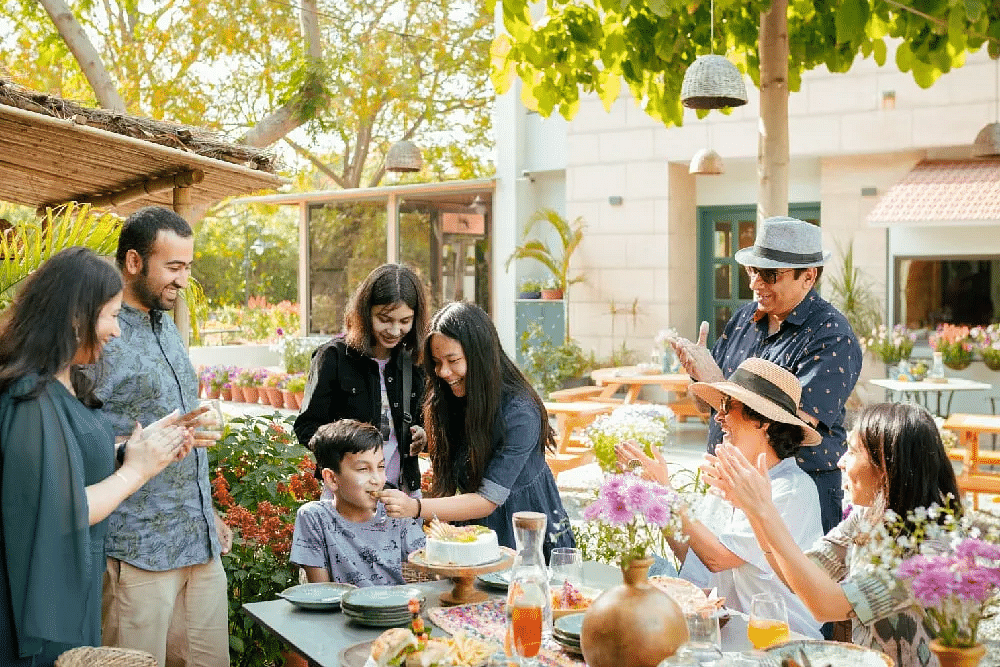 Group of people standing and talking around an outdoor table at Karma Chalets.