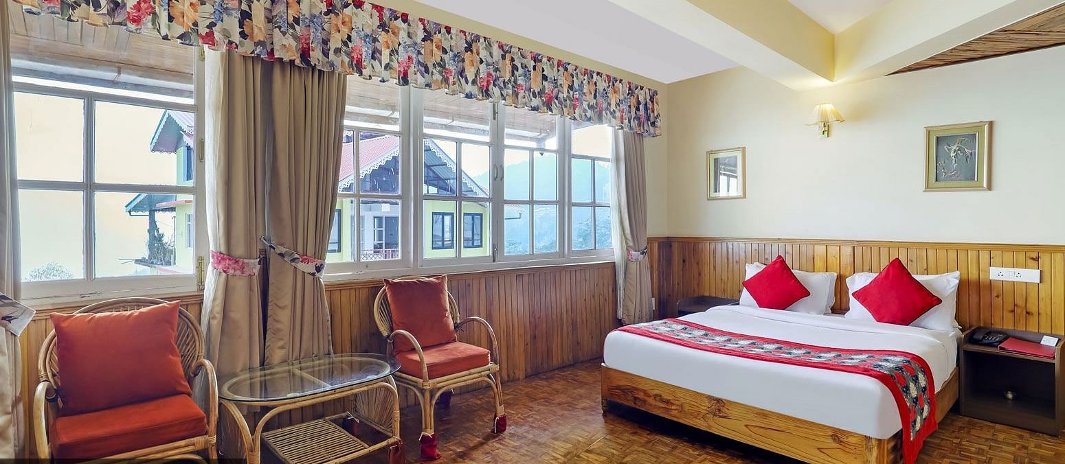 A room with a bed, chairs, and a glass window | Summit Newa Regency & Spa, Pelling