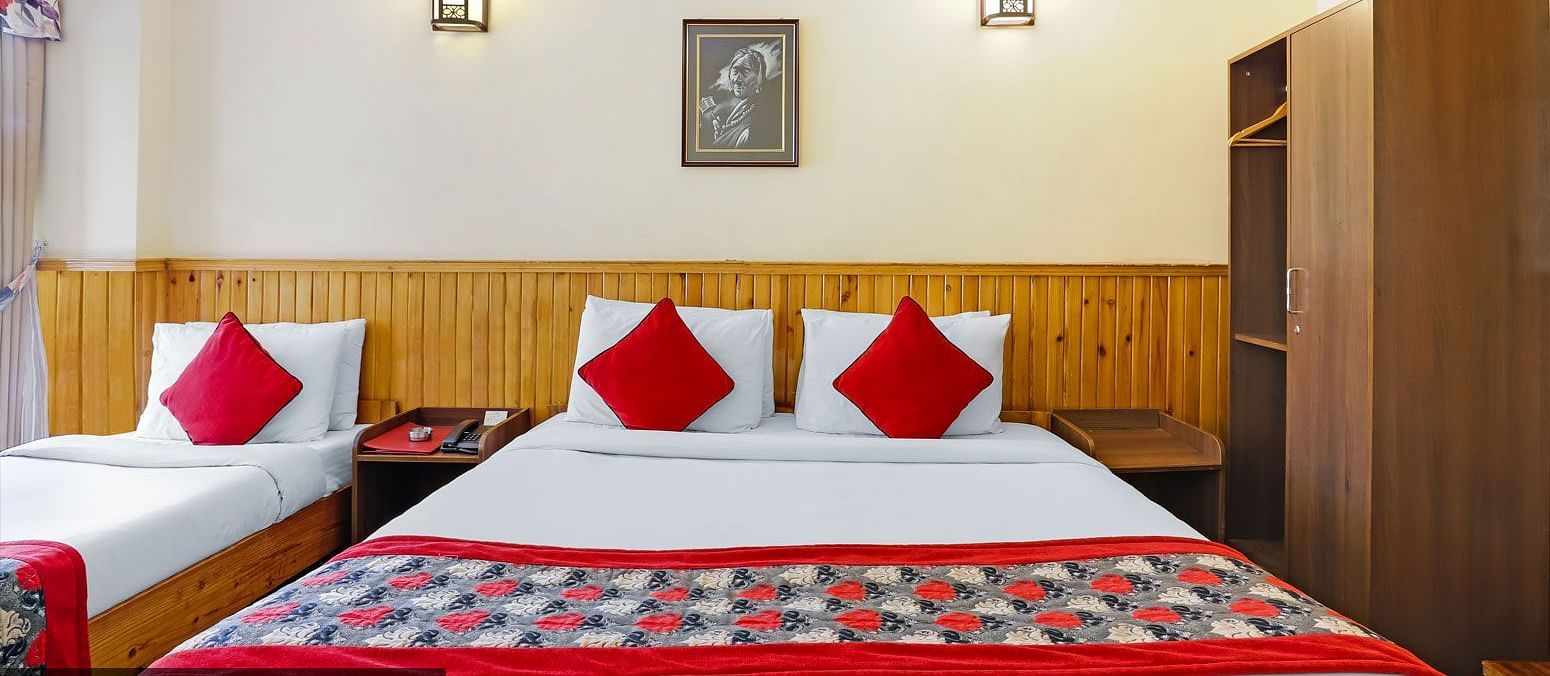 A front view of the beds placed in a room that has a glass window | Summit Newa Regency & Spa, Pelling