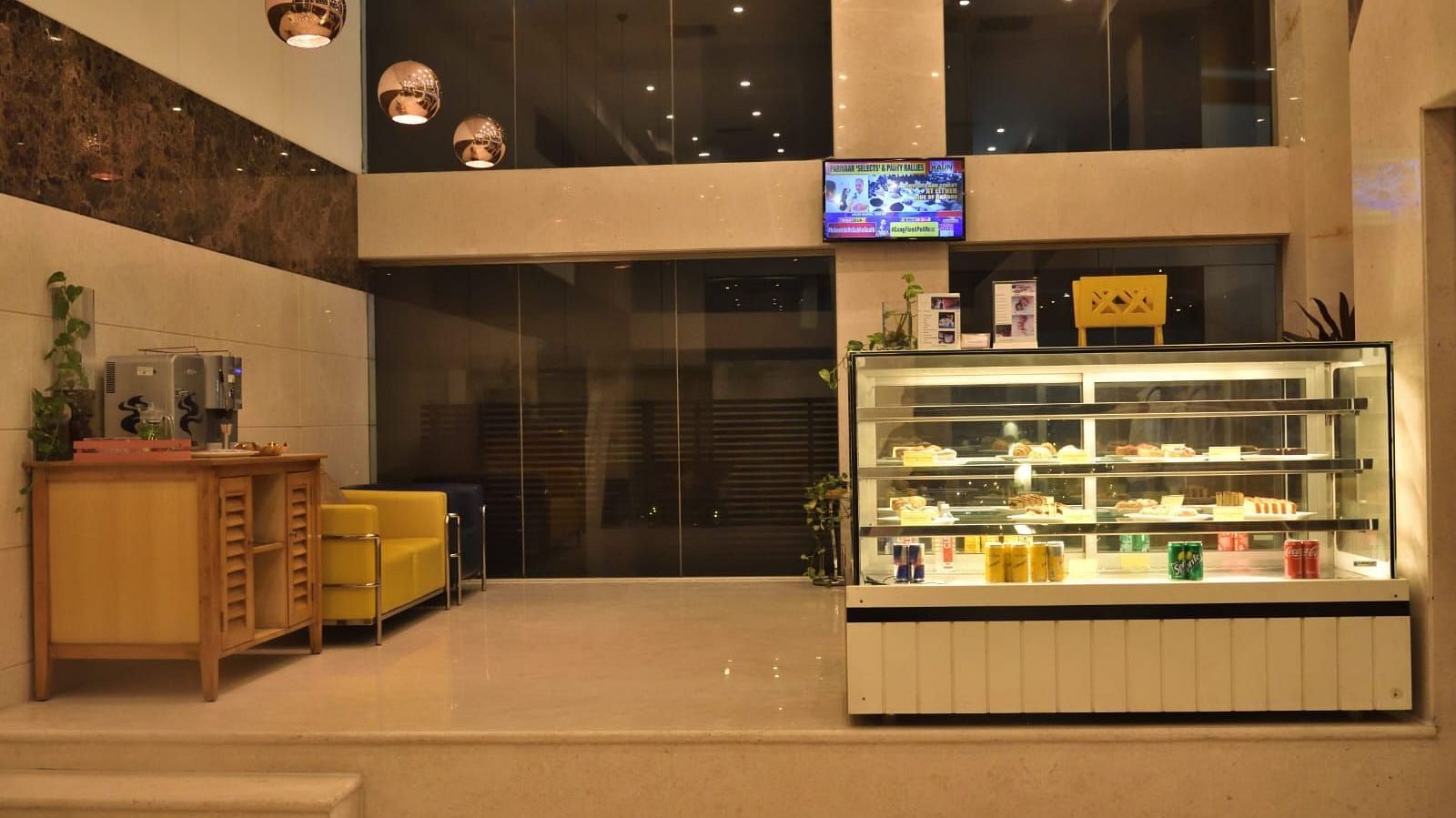 The Lobby Bake House features a display fridge with food, seating, and warm lighting, suggesting a welcoming atmosphere at The Cunningham Hotel