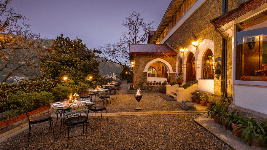 An image of naini retreat, nainital, with a scenic view of  building with a stone exterior and arched doorways. The building is illuminated by warm lights, creating a cozy atmosphere. 