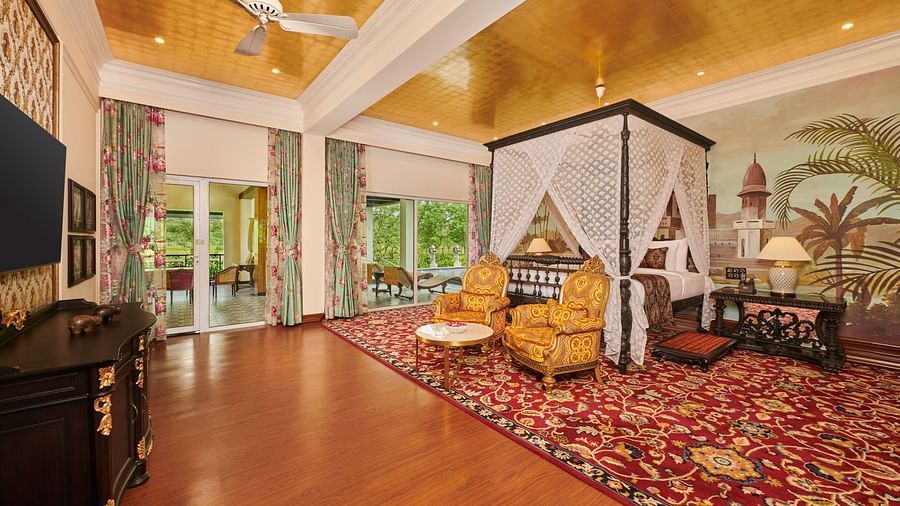 Four poster bed in a spacious suite with vintage decor and carpeted flooring.