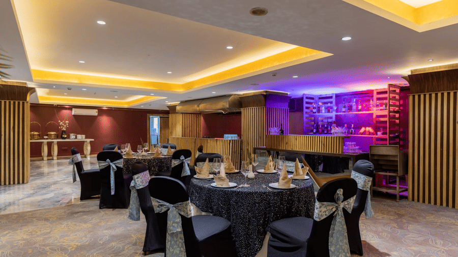 Galaxy Banquet Hall at Papaya Tree Hotels showcasing a refined indoor setup with decorative lighting, table arrangements, and a bar backdrop for social gatherings.