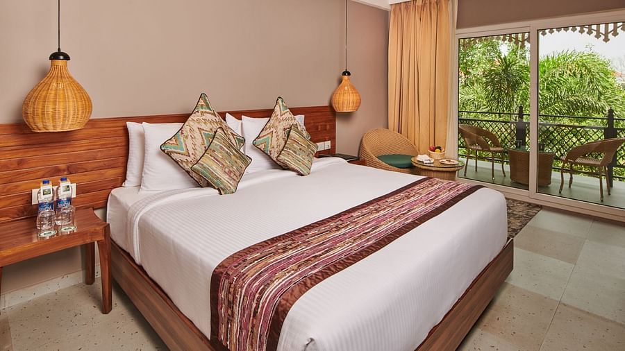 A room at Swosti Chilika Resort with a double bed and a balcony with seating arrangement