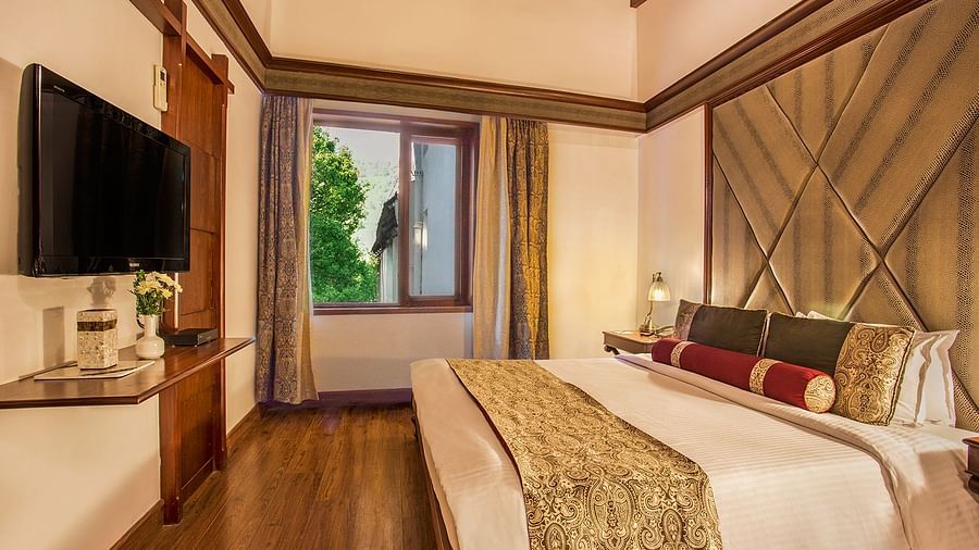 A side view of a suite with bed, TV and a window - the naini retreat, nainital.