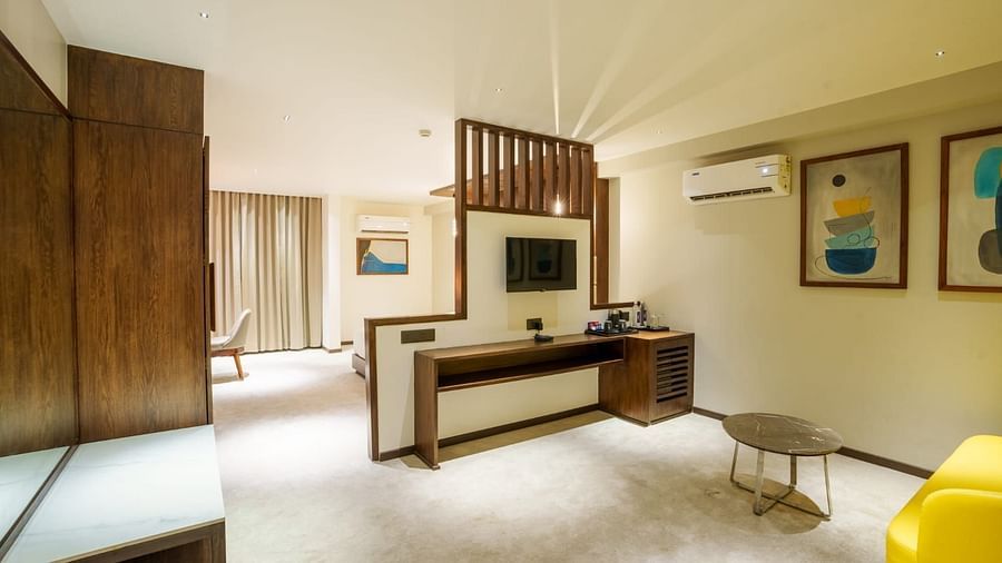 A living area in our hotel room with a television, a draw and a comfortable yellow sofa