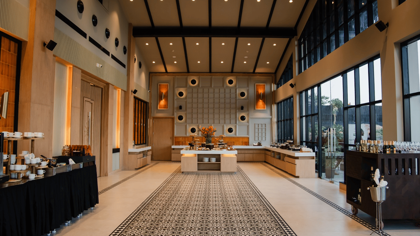 Ballroom with a high, gable-style ceiling and open layout, offering a spacious setting with comfortable sofas and a dining area for a buffet