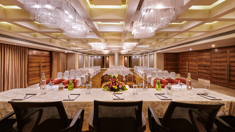 Event hall at The Pride Premier Nagpur featuring a conference table and chairs for the guests and there are several chairs in front of the table.