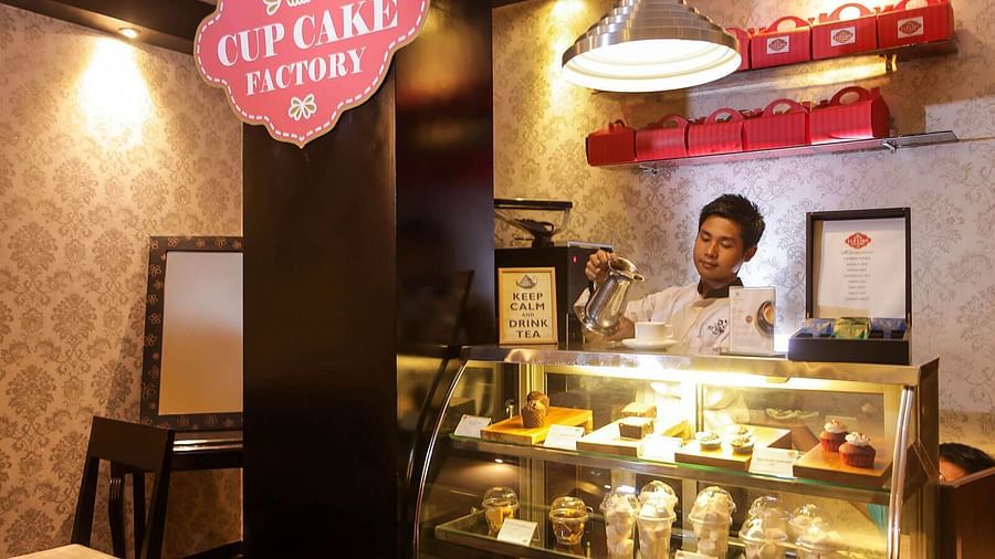 a man standing behind a bakery counter