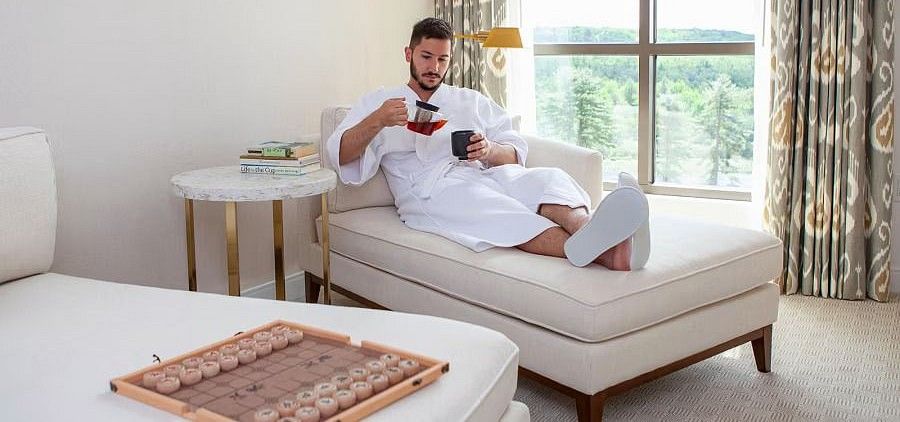 man sitting on the sofa, pouring beverage into a cup
