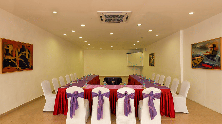 Frangi Pani Hall set up with round tables in red linens and purple sashes at Chariot Beach Resorts, perfect for elegant gatherings.