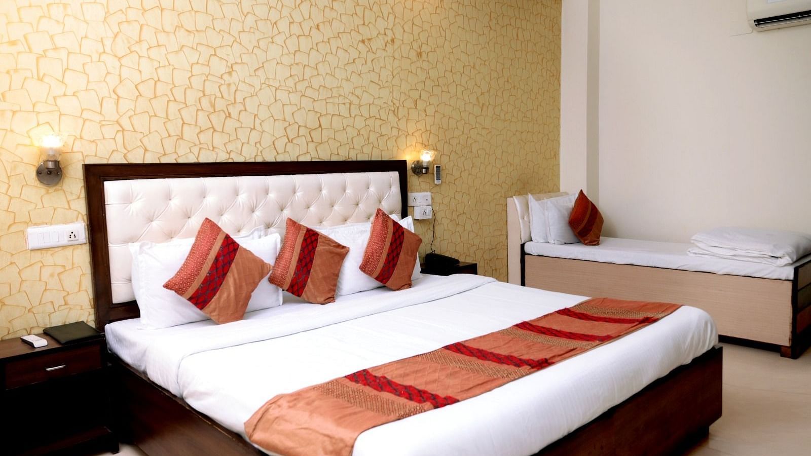 A luxurious hotel room with a king-size bed, golden accent wallpaper, warm lighting, and a modern aesthetic - Hotel Diamond Inn, Chandigarh