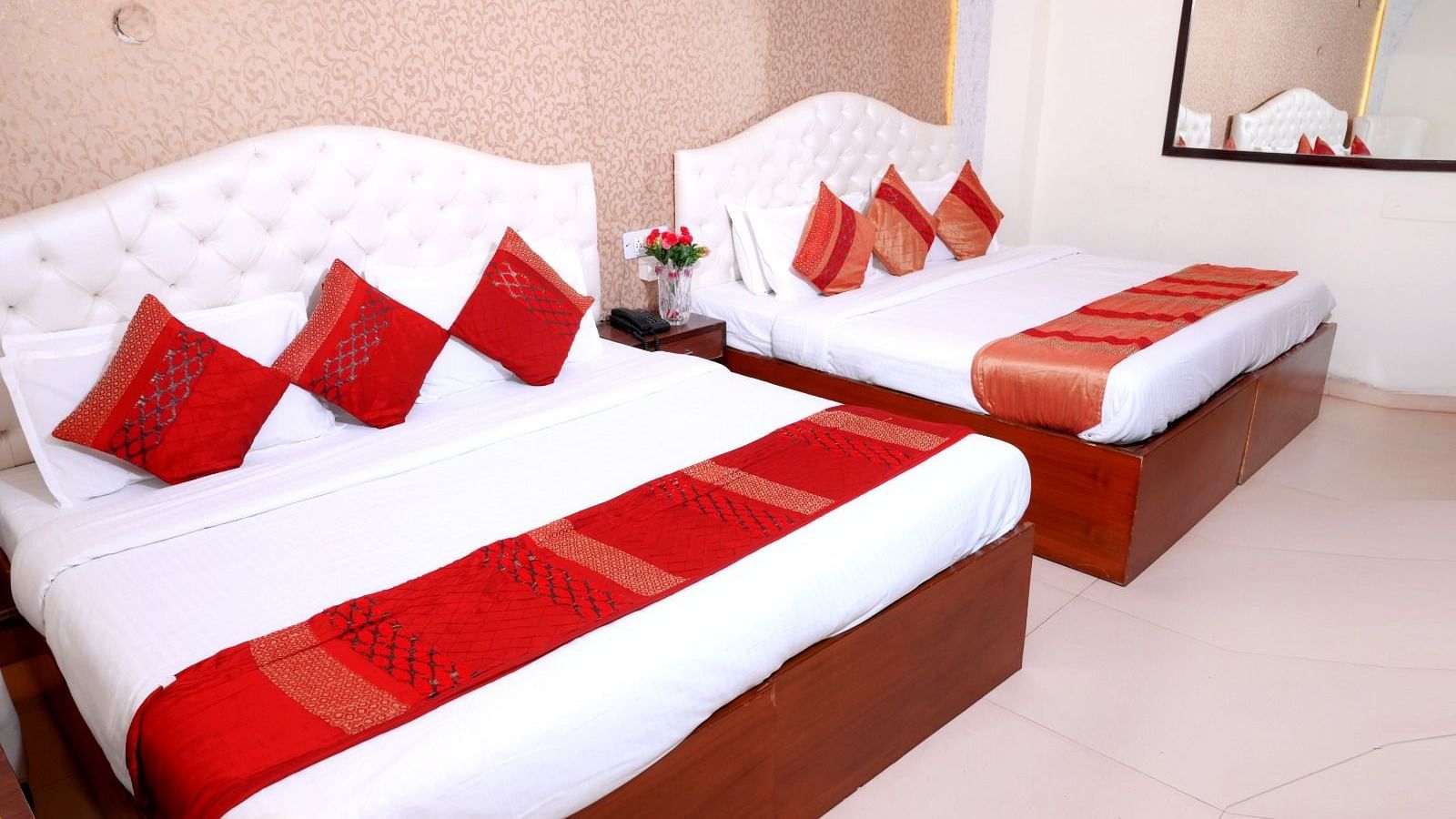 A spacious hotel room featuring a king-size bed, an additional single bed, plush white headboards, and red accent pillows - Hotel Diamond Inn, Chandigarh