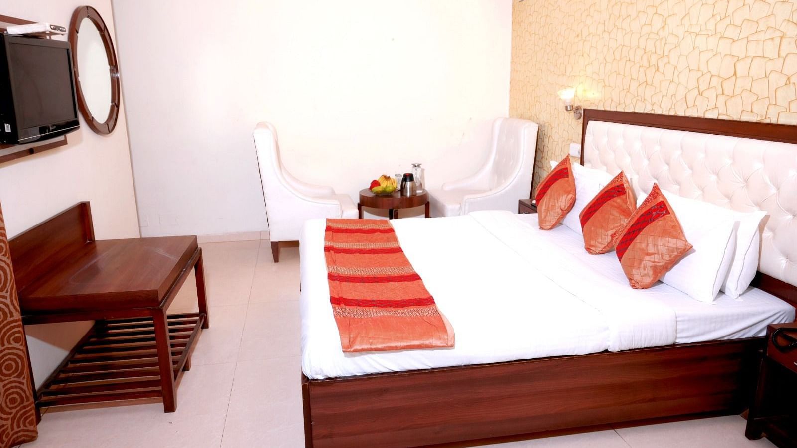 A modern hotel room with a king-size bed, a textured gold accent wall, and a small seating area - Hotel Diamond Inn, Chandigarh
