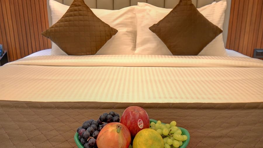 An image of a bed with a plate filled with a variety of fresh fruits placed on top at Hari Govindas, Siddappa Square.