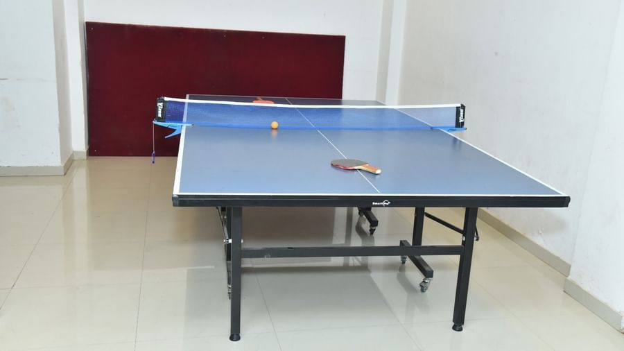 A table tennis setup in an indoor room with a table, net, two paddles, and a ball placed on it, at Highland Resort.