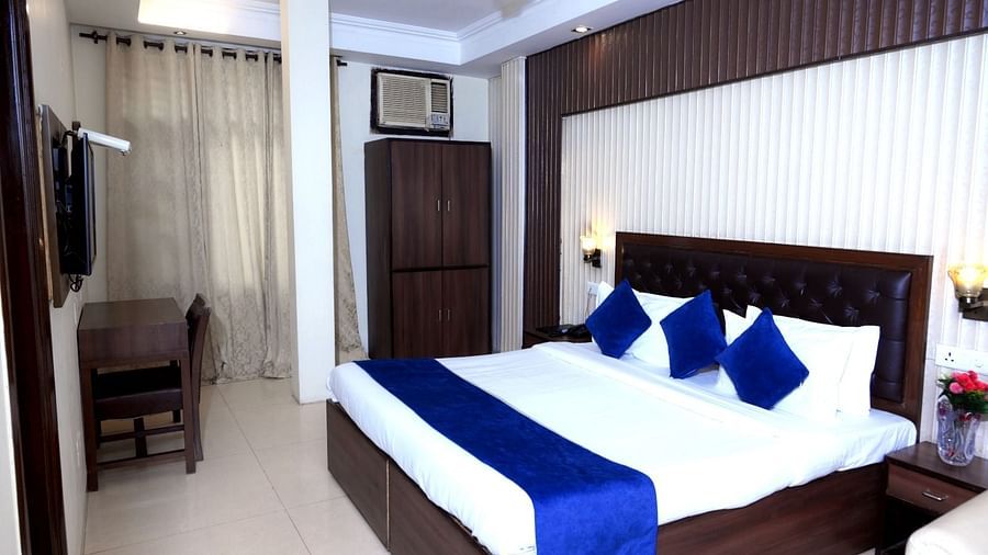  A cosy hotel room with a king-size bed, blue and white linens, wooden furniture, and soft lighting - Hotel Diamond Inn, Chandigarh