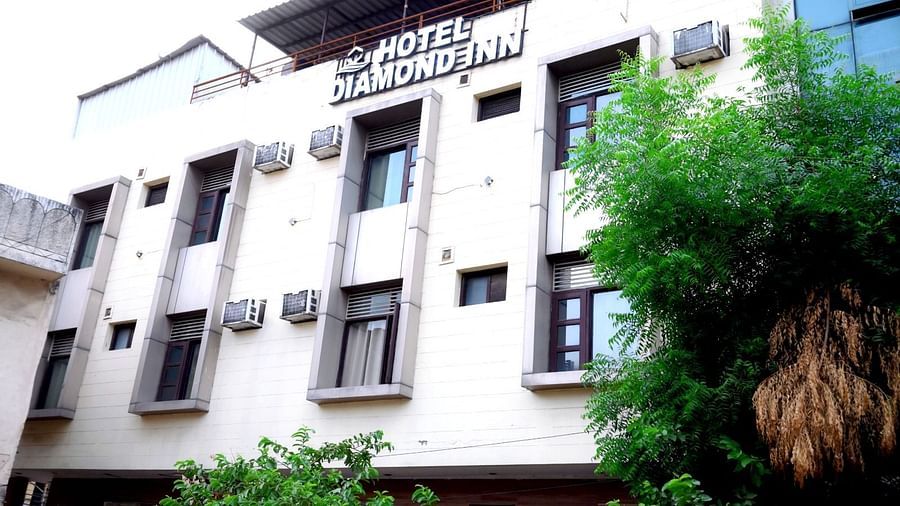 The exterior of a hotel building with a white facade, green trees, and signage displaying the hotel's name - Hotel Diamond Inn, Chandigarh