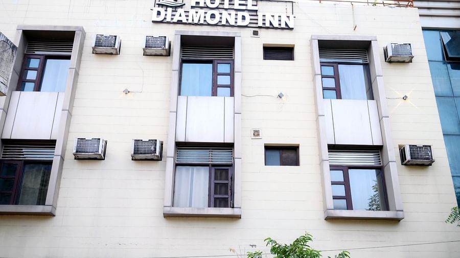 The exterior of a hotel building with a white facade, green trees, and signage displaying the hotel's name - Hotel Diamond Inn, Chandigarh